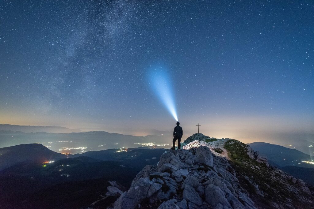 Buch-Tipp: Mann mit Stirnlampe auf Bergspitze unter Sternenhimmel. The Reality Revolution von Brian Scott.