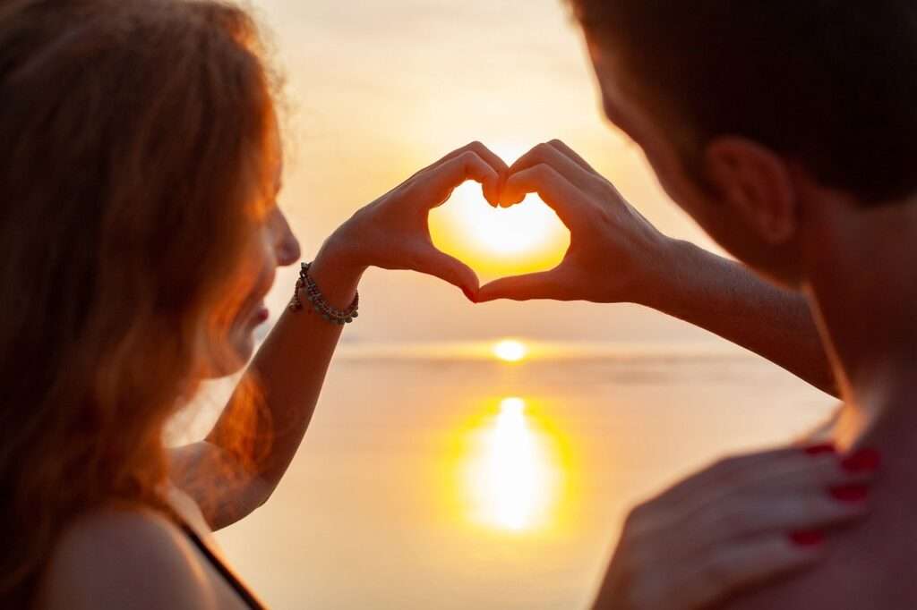 Honeymoon Effekt: Paar formt Herz vor Sonnenuntergang. Liebe geht durch die Zellen, wie im Buch von Bruce Lipton.