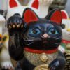 Glückskatzen: Schwarze und weiße Maneki Neko Figuren für Reichtum. Buchtipp: Der Almanach von Naval Ravikant.